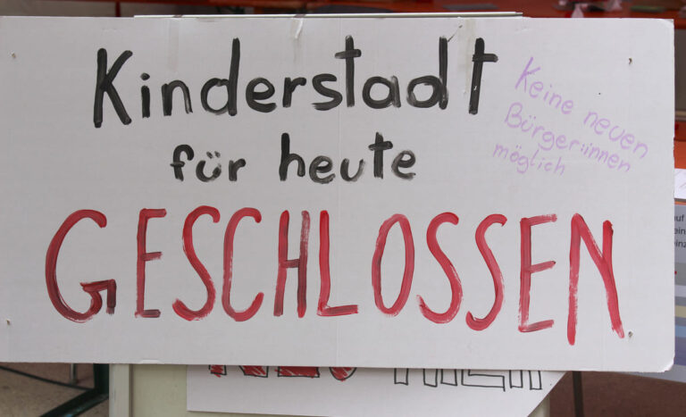 Handgeschriebenes Plakat auf dem steht, dass die Kinderstadt - vorübergehend - geschlossen werden musste