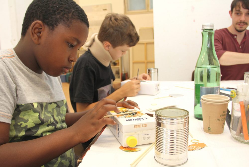 Kinder bauen aus einem Getränkekarton ein Saiteninstrument