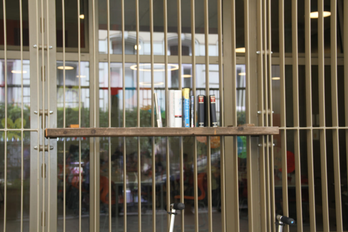 Kleine offene Bibliothek zwischen Gitterstäben an der Schulfassade
