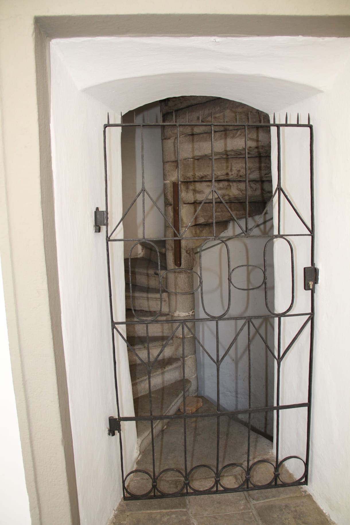 Kleines Gittertor bei einer Wendeltreppe nach oben