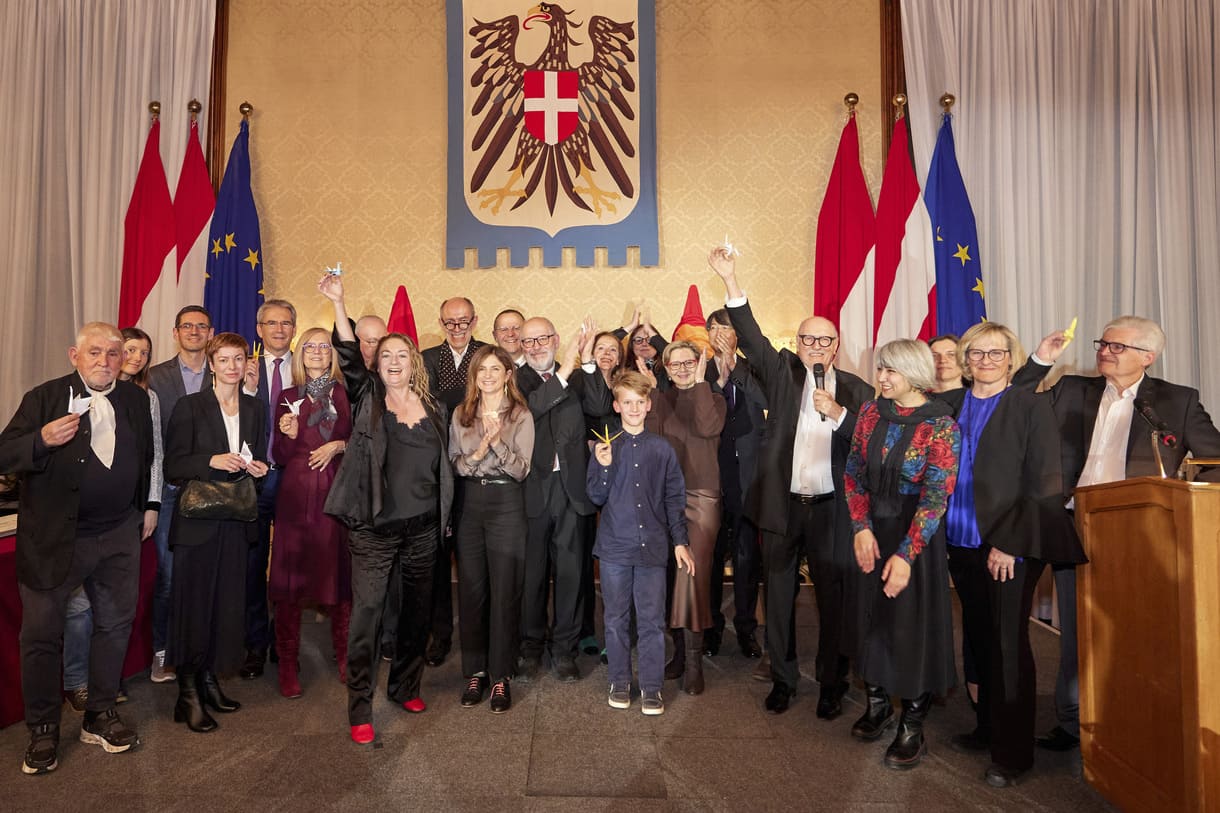 Jurymitglieder, Sponsoren und Preisträger:innen mit Papierkranichen (Friedenssymbol) auf der Bühne.