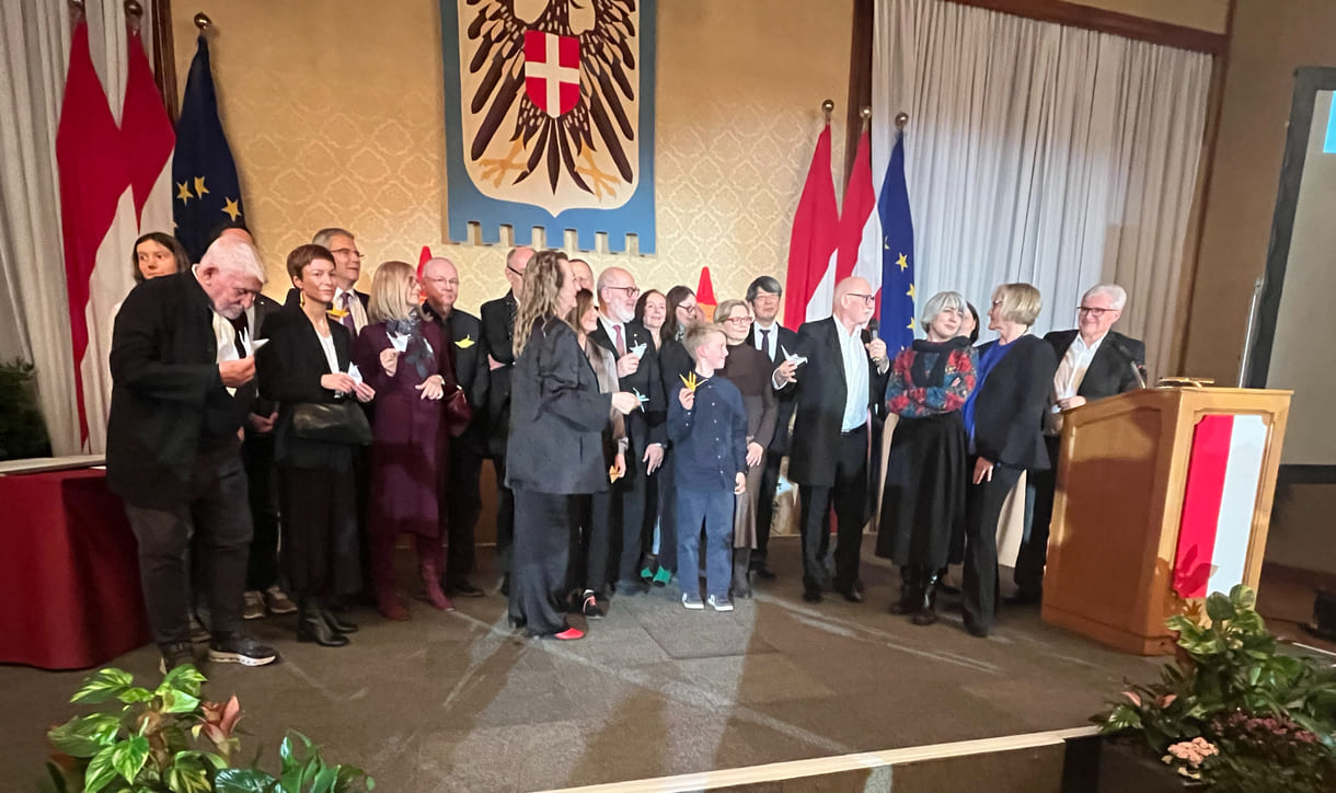 Großgruppenfot der anwesenden Gewinner:innen, Laudator:innen, Sponsor:innen... - mit gefalteten Papierkranichen