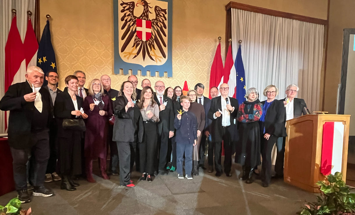 Großgruppenfot der anwesenden Gewinner:innen, Laudator:innen, Sponsor:innen... - mit gefalteten Papierkranichen