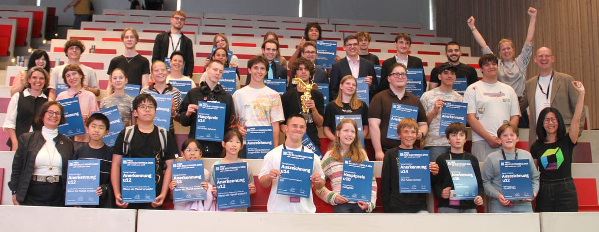 Gruppenfoto aller Preisträger:innen, die nach Linz kommen konnten, mit Jurymitgliedern und Preis-Überreicher:innen