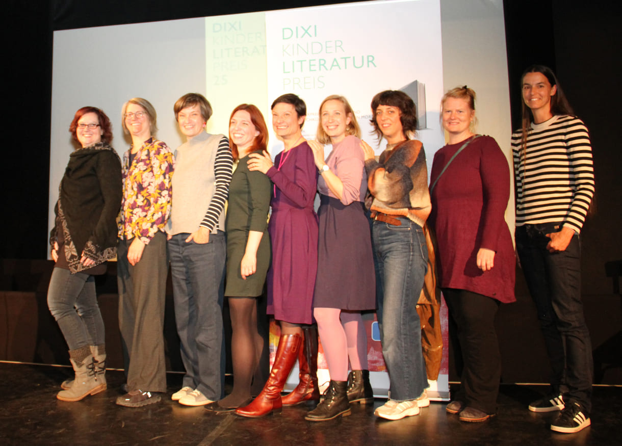 Gruppenfoto der anwesenden Preisträger:innen: Kathrin Steinberger (Text, 2003), Elisabeth Etz (Text, 2004), Leonora Leitl (Illustration, 2013), Katharina Fohringer-Hackl (Text, 2023), Lena Raubaum (Lyrik, 2016), Ella Kaspar (Text, 2021), Leonie Schlager (Illustration, 2019), Juliana Guger (Illustration, 2024), Anita Hetzenauer (Text, 2025)