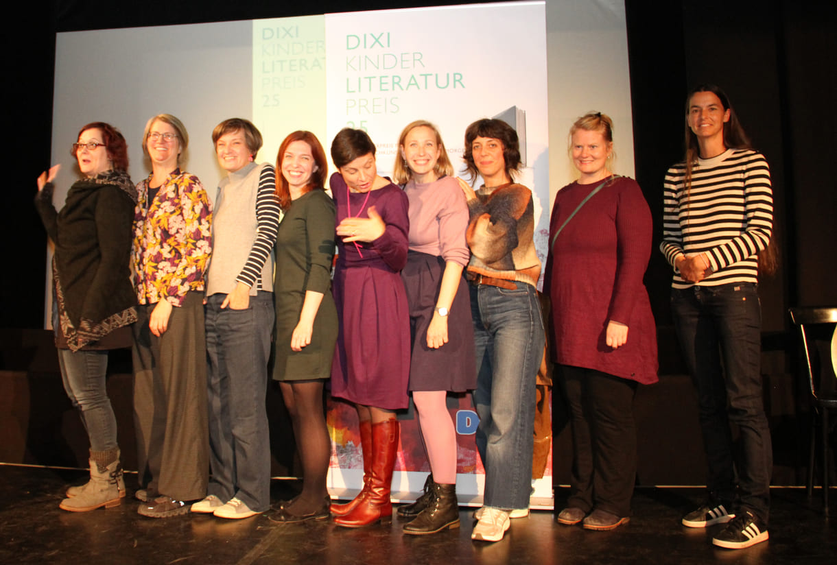 Gruppenfoto der anwesenden Preisträger:innen: Kathrin Steinberger (Text, 2003), Elisabeth Etz (Text, 2004), Leonora Leitl (Illustration, 2013), Katharina Fohringer-Hackl (Text, 2023), Lena Raubaum (Lyrik, 2016), Ella Kaspar (Text, 2021), Leonie Schlager (Illustration, 2019), Juliana Guger (Illustration, 2024), Anita Hetzenauer (Text, 2025)