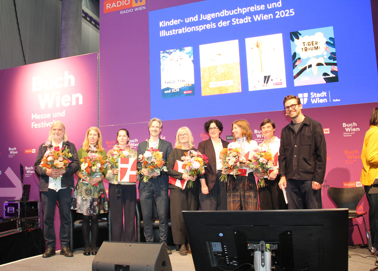 Gruppenfoto der Preisräger:innen mit Stadt-Wien-Vertreterin und Moderator