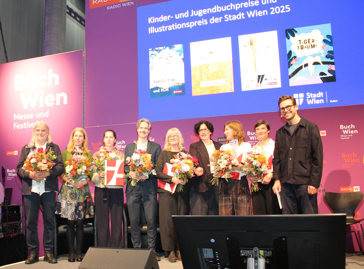 Gruppenfoto der Preisräger:innen mit Stadt-Wien-Vertreterin und Moderator