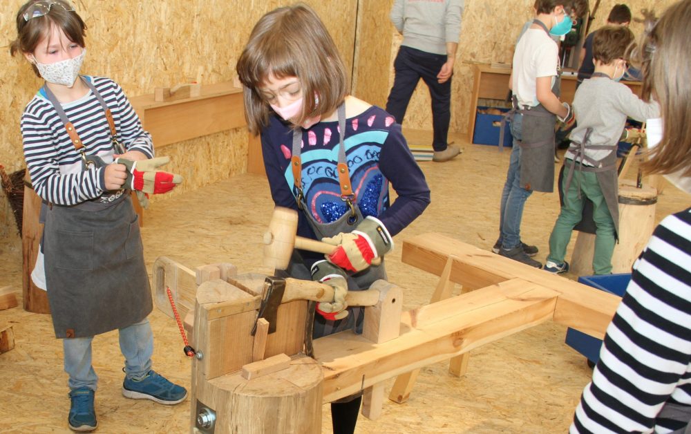 Kinder hacken mit - gesicherter Hacke - und Hammer ein Stück Holz ab