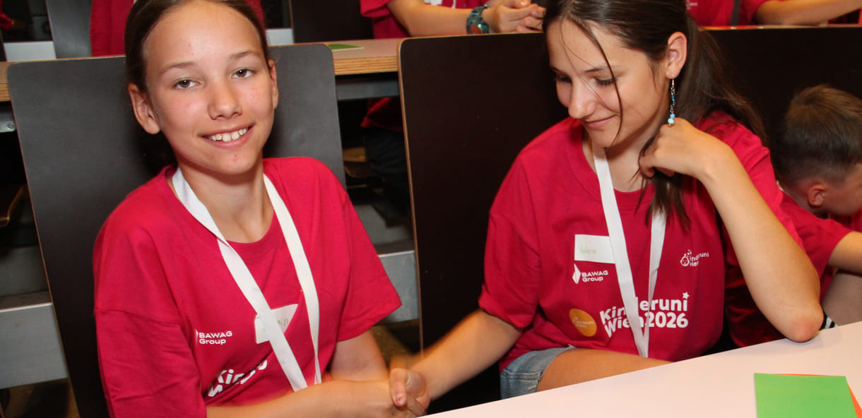 Kinderuni-Studierende schütteln einander die Hände - Glitzer wird dabei weitergegeben