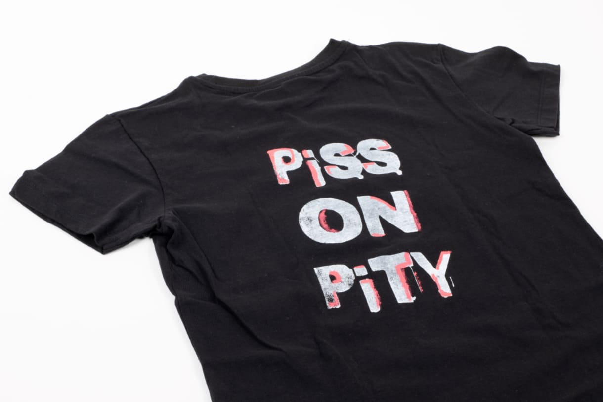 T-Shirt: „Piss on Pity” (Piss / Schiff / Brunz auf Mitleid), eingebracht in die Sammlung von 