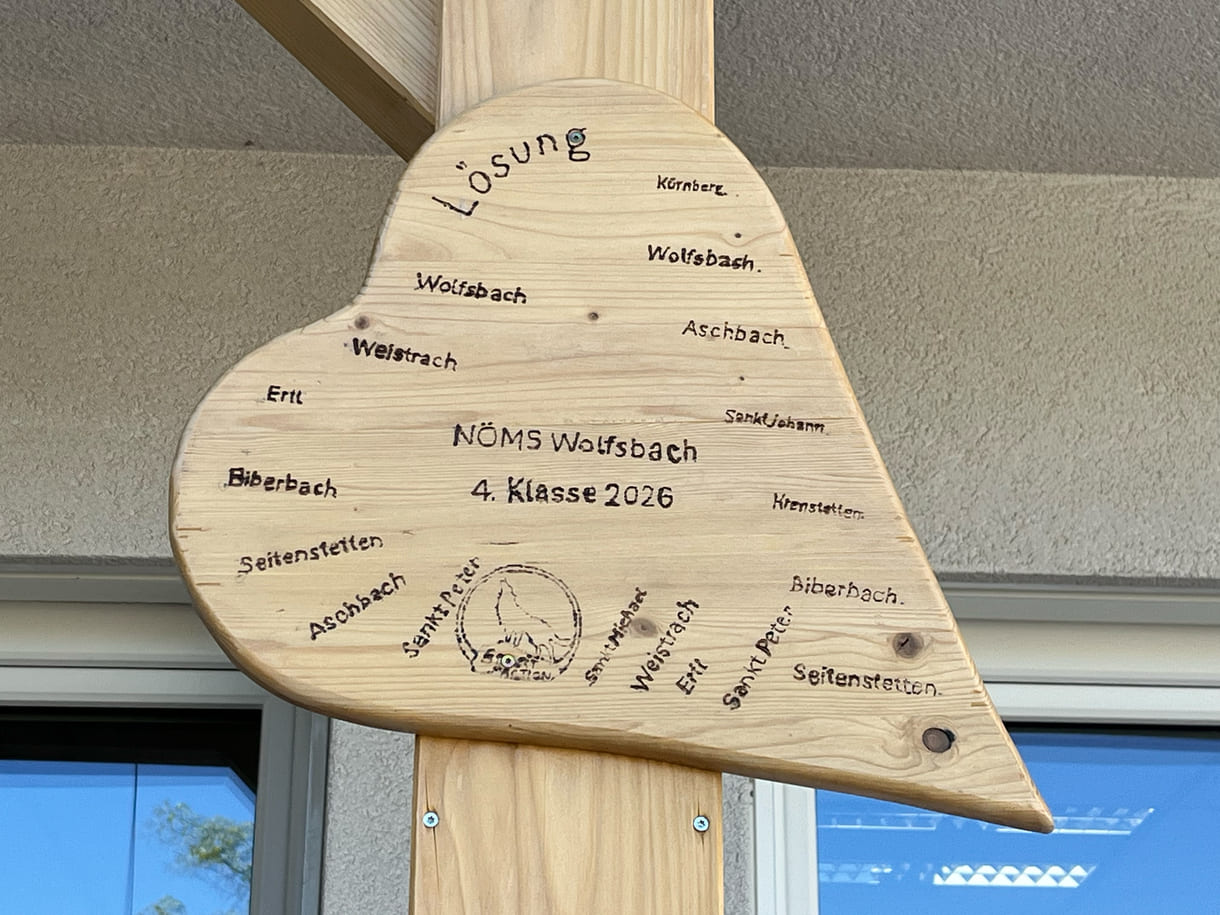 Vor der Mittelschule Wolfsbach hängen bereits von Schüler:innen gestaltete Holz-Herzen - unter anderem mit Informationen bzw. einem Quiz zur 