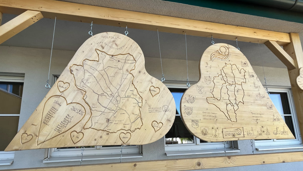 Vor der Mittelschule Wolfsbach hängen bereits von Schüler:innen gestaltete Holz-Herzen - unter anderem mit Informationen bzw. einem Quiz zur 