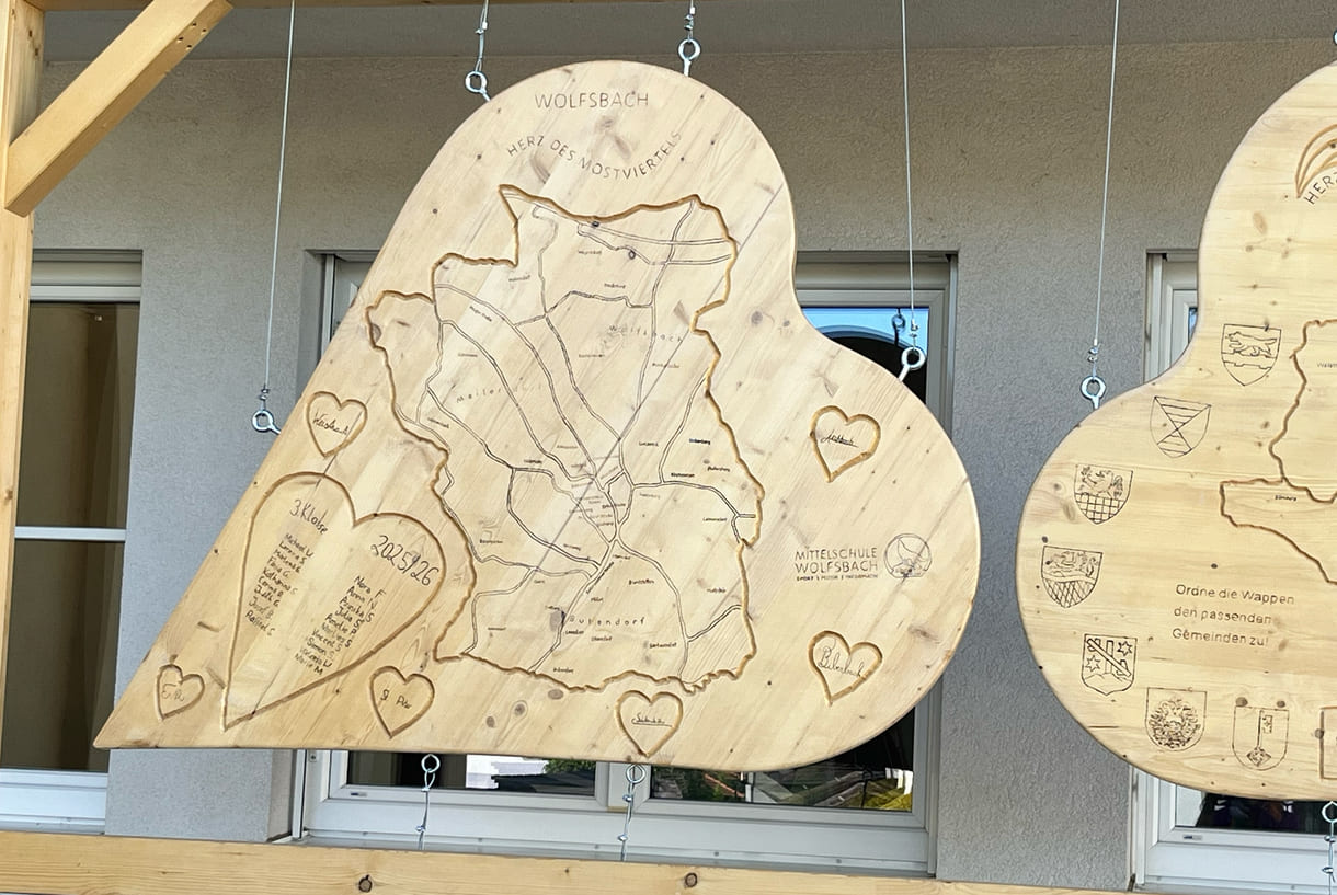 Vor der Mittelschule Wolfsbach hängen bereits von Schüler:innen gestaltete Holz-Herzen - unter anderem mit Informationen bzw. einem Quiz zur 