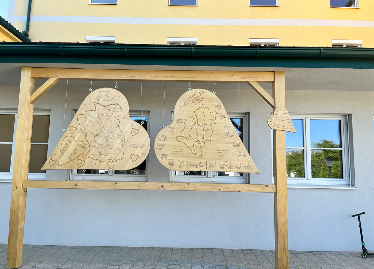 Vor der Mittelschule Wolfsbach hängen bereits von Schüler:innen gestaltete Holz-Herzen - unter anderem mit Informationen bzw. einem Quiz zur 