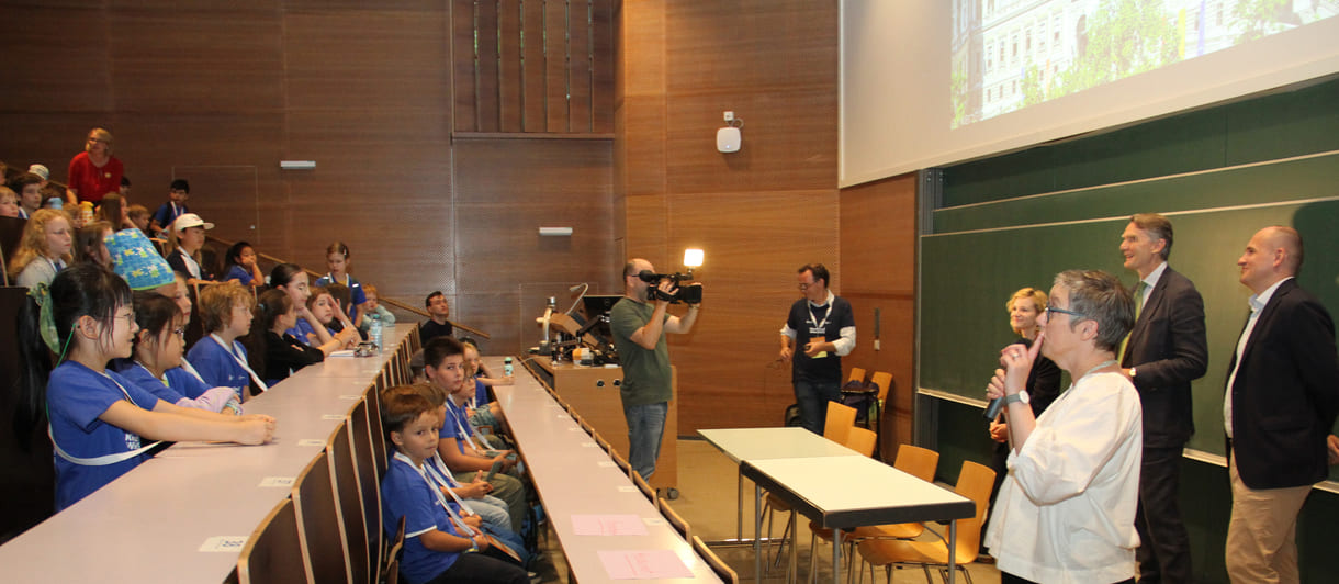 Hoher Besuch im Hörsaal - neben dem Quantenphysiker Markus Aspelmeyer die Wissenschaftsministerin Eva-Maria Holzleitner, Uni-wien-Rektor Sebastian Schütze, Sponsprvertreter Enver Siručić und ganz rechts außen nur teils zu sehen Karoline Iber, Ober-organisatorin der Kinderuni wien - von Anbeginn an