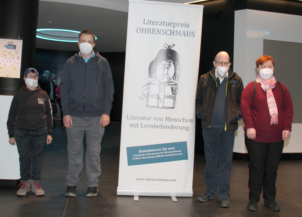 Vier Literat:innen: Sylvia Hochmüller, Michael Wilhelm (links vom Plakat "Ohrenschmaus") sowie Herbert Schinko und Inge Weinberger (rechts)