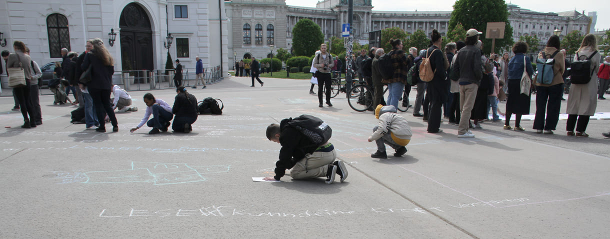 Jugendliche malen mit Kreide Sprüche auf den Boden