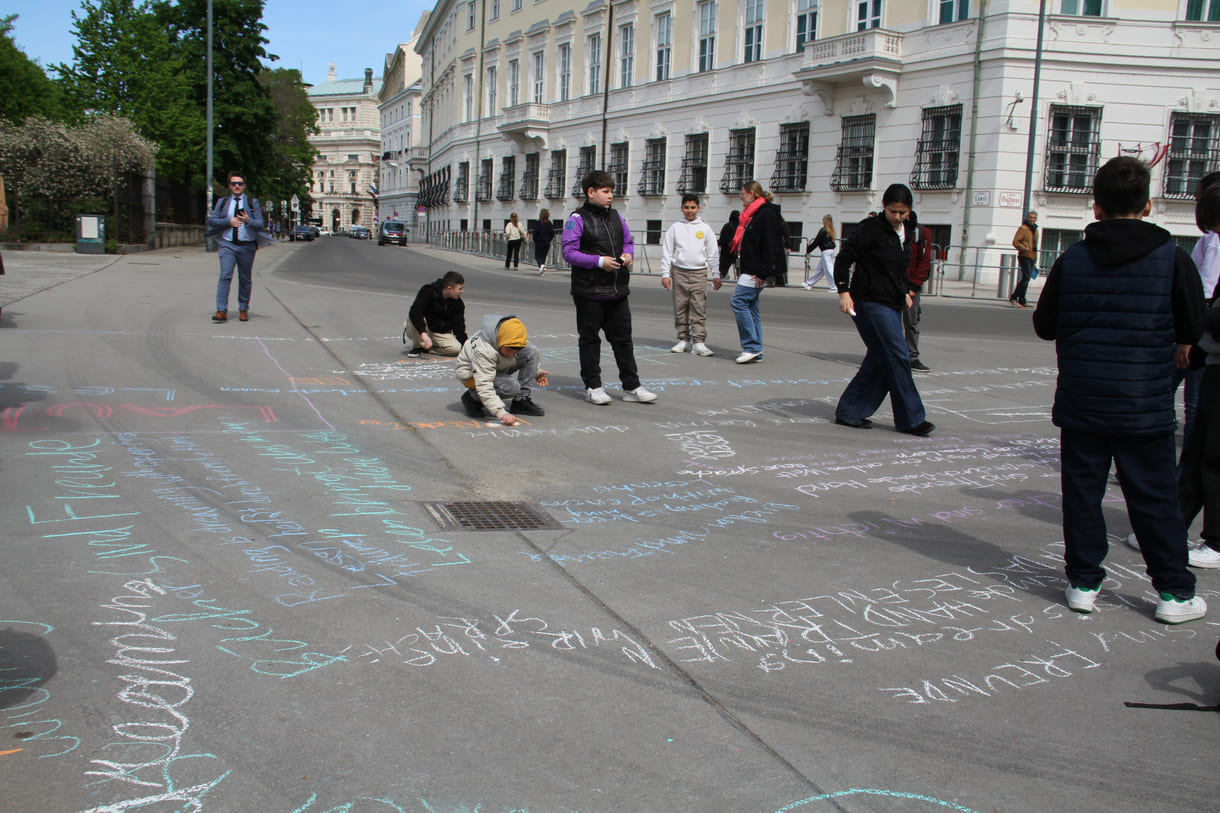 Jugendliche malen mit Kreide Sprüche auf den Boden