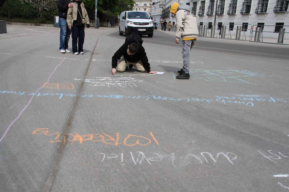 Jugendliche malen mit Kreide Sprüche auf den Boden