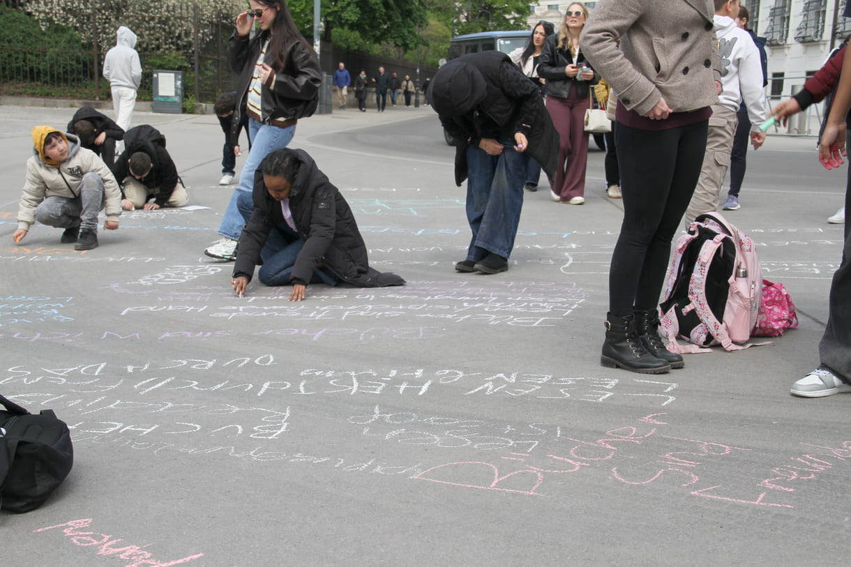 Jugendliche malen mit Kreide Sprüche auf den Boden
