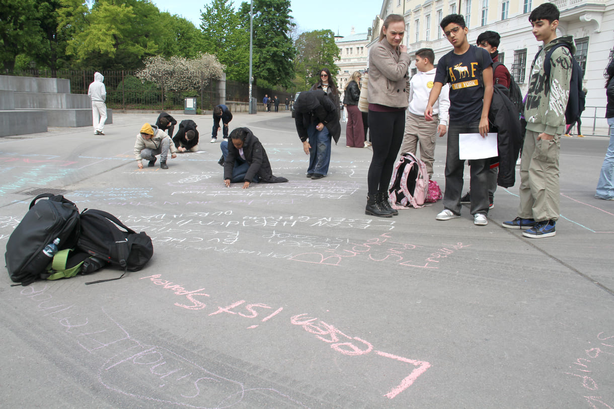 Jugendliche malen mit Kreide Sprüche auf den Boden