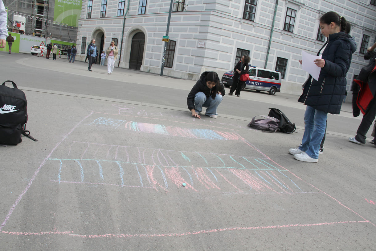 Jugendliche malen mit Kreide Sprüche auf den Boden