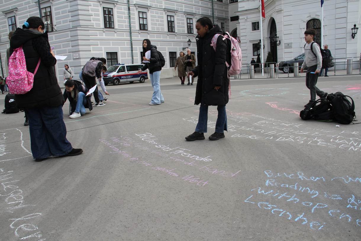 Jugendliche malen mit Kreide Sprüche auf den Boden