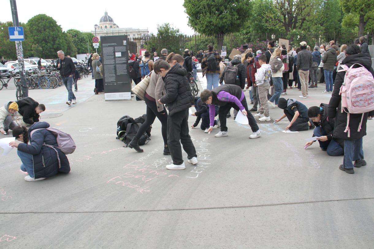 Jugendliche malen mit Kreide Sprüche auf den Boden