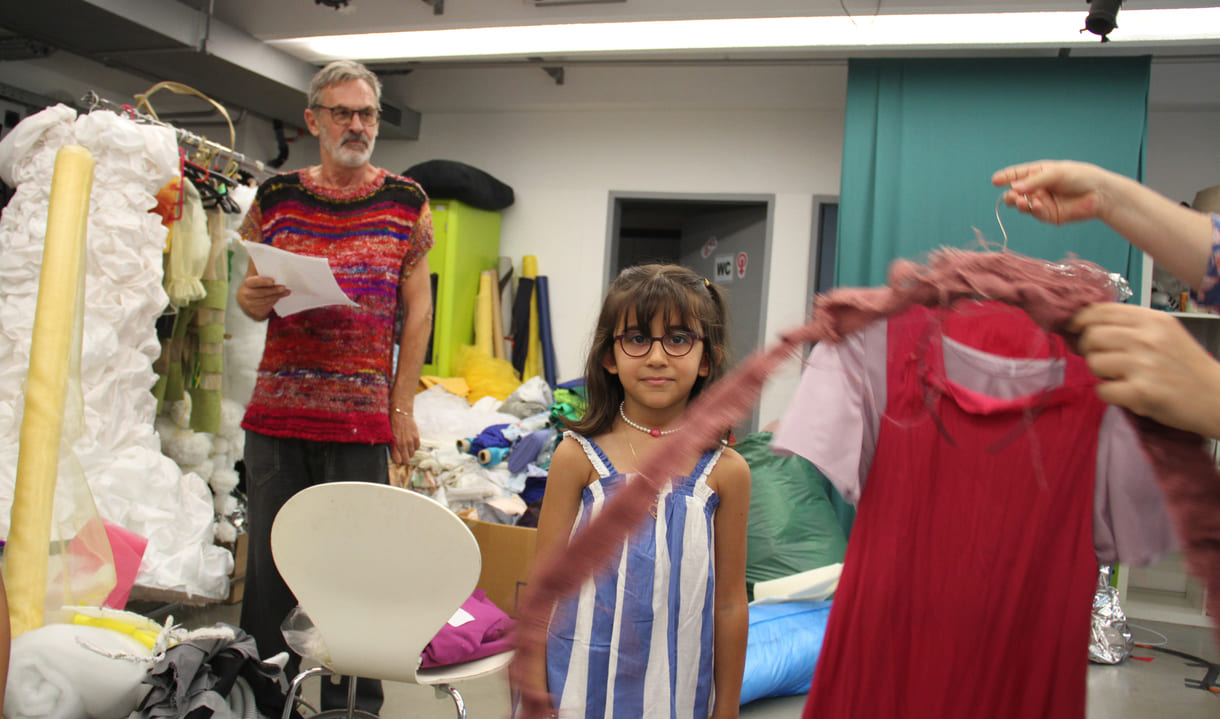 Julia Saidan (7) mit den - noch nciht fertigen - Stoff gewordenen Teilen ihres gezeichneten Designs sowie mit Leo, dem ERfinder von Kids in Fashion und Sarah, die für die Umsetzung vieler der Designs in der Werkstatt verantwortlich ist
