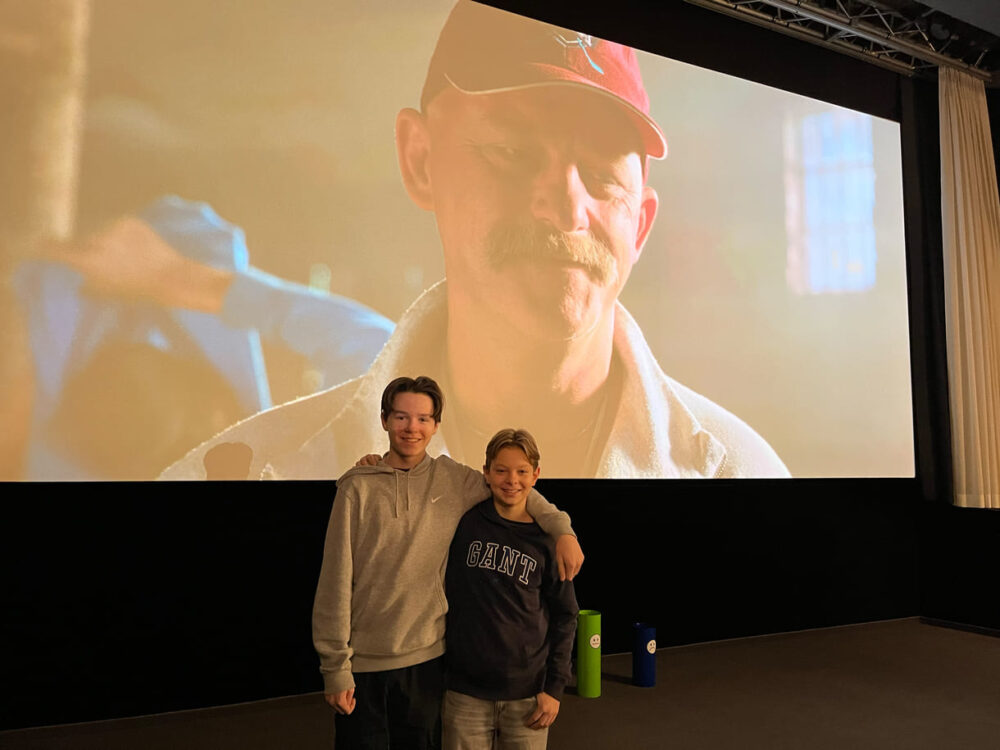 Tom Brenton (im Film Dom) und Fabian Šetlík (m Film Dvořka) im Kino - auf der Leinwand der Trainer des Film-Hockey-Teams