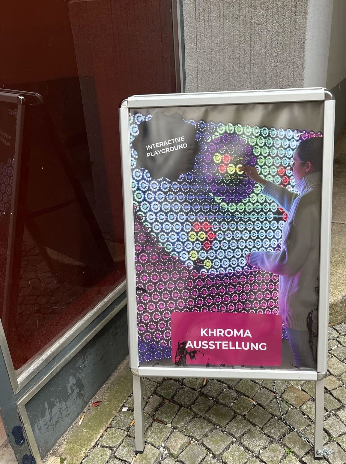 Plakatständer im Hof zeigt den Weg zur Ausstellung