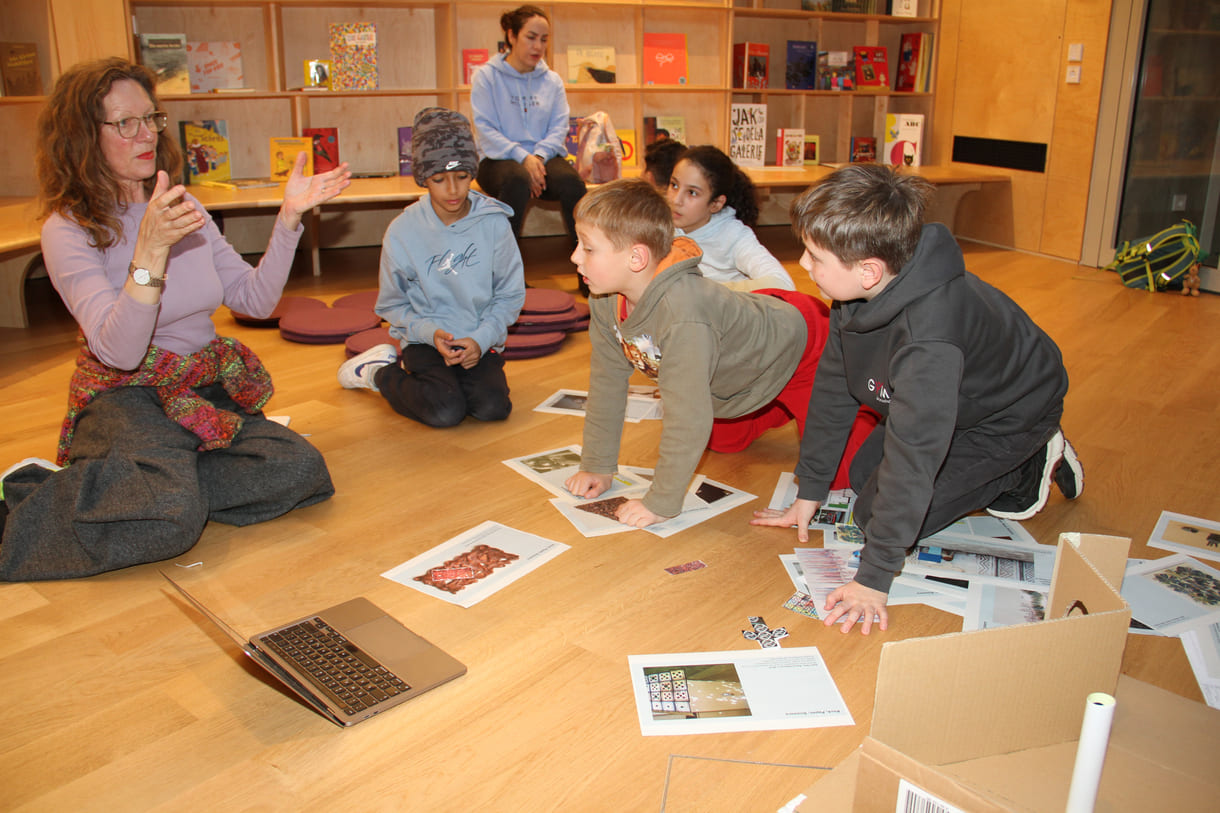 Kinder in der Runde der Ideengeber:innen - mit Bildern und Fotos von Objekten der künftigen Gemeinschaftsausstellung