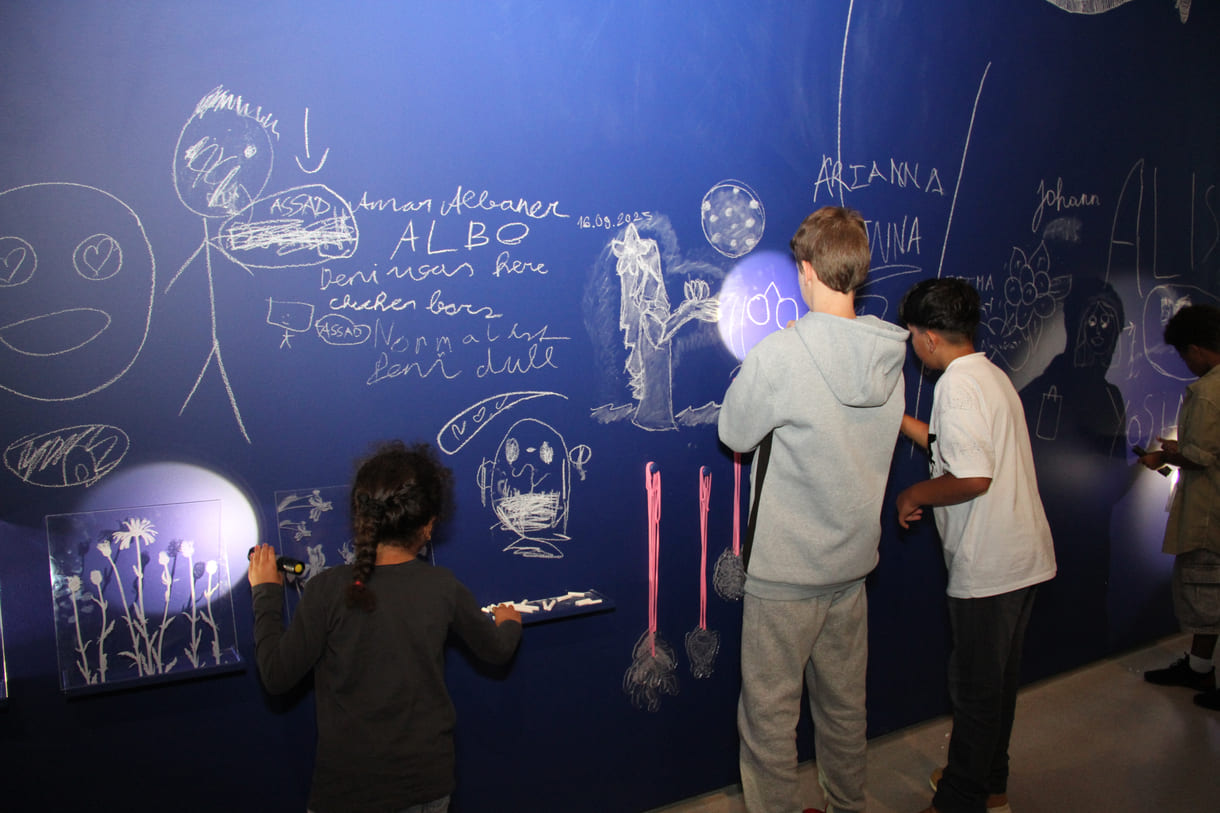 In der Ausstellungshalle ist eine ganze Wand für Kreidezeichnung der Besucher:innen reserviert