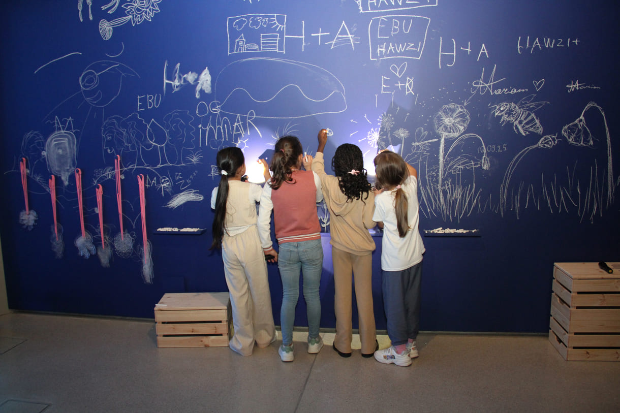 In der Ausstellungshalle ist eine ganze Wand für Kreidezeichnung der Besucher:innen reserviert