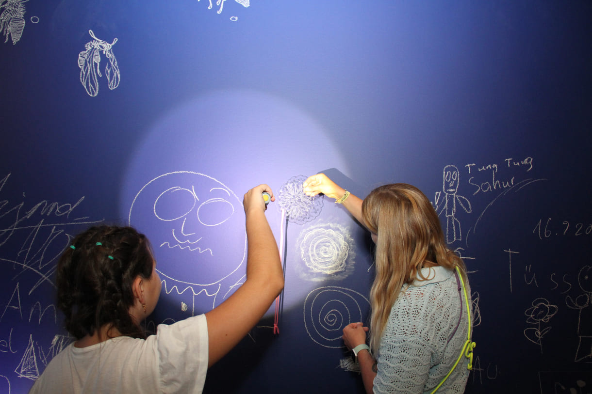 In der Ausstellungshalle ist eine ganze Wand für Kreidezeichnung der Besucher:innen reserviert