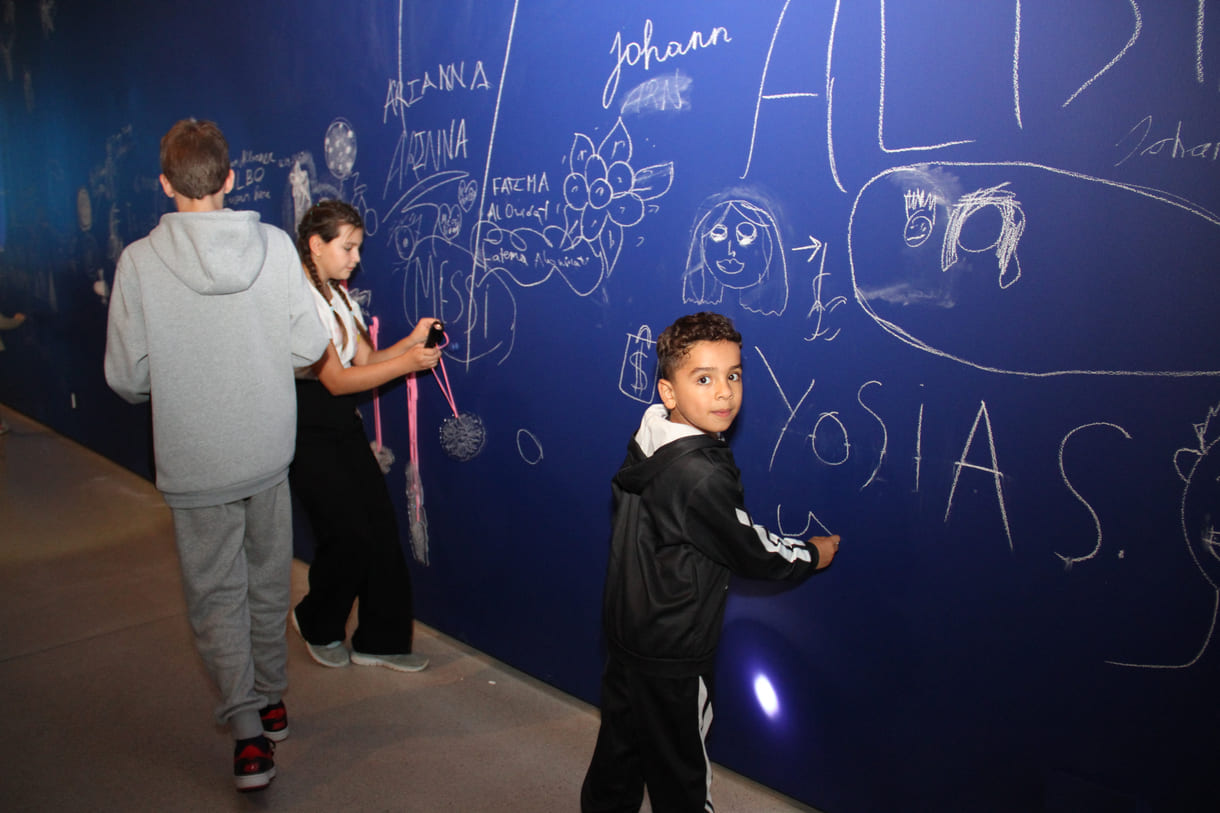 In der Ausstellungshalle ist eine ganze Wand für Kreidezeichnung der Besucher:innen reserviert