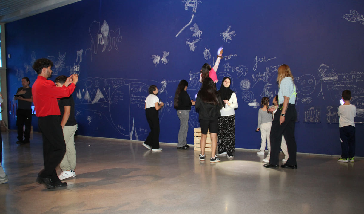 In der Ausstellungshalle ist eine ganze Wand für Kreidezeichnung der Besucher:innen reserviert