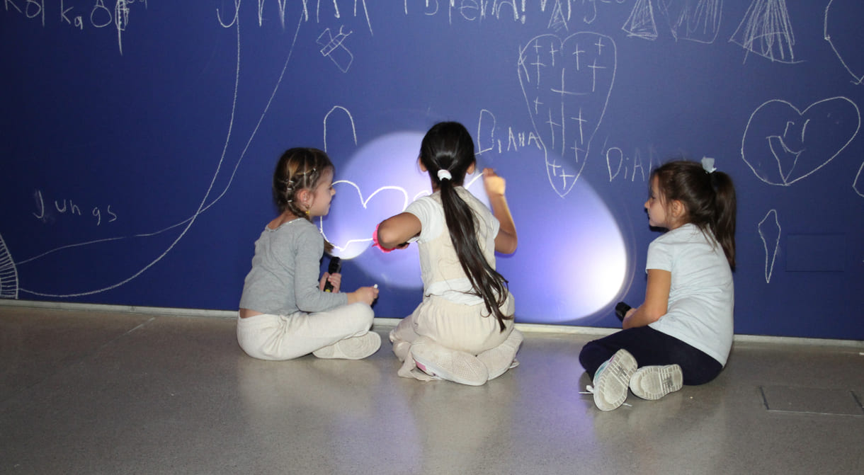 In der Ausstellungshalle ist eine ganze Wand für Kreidezeichnung der Besucher:innen reserviert