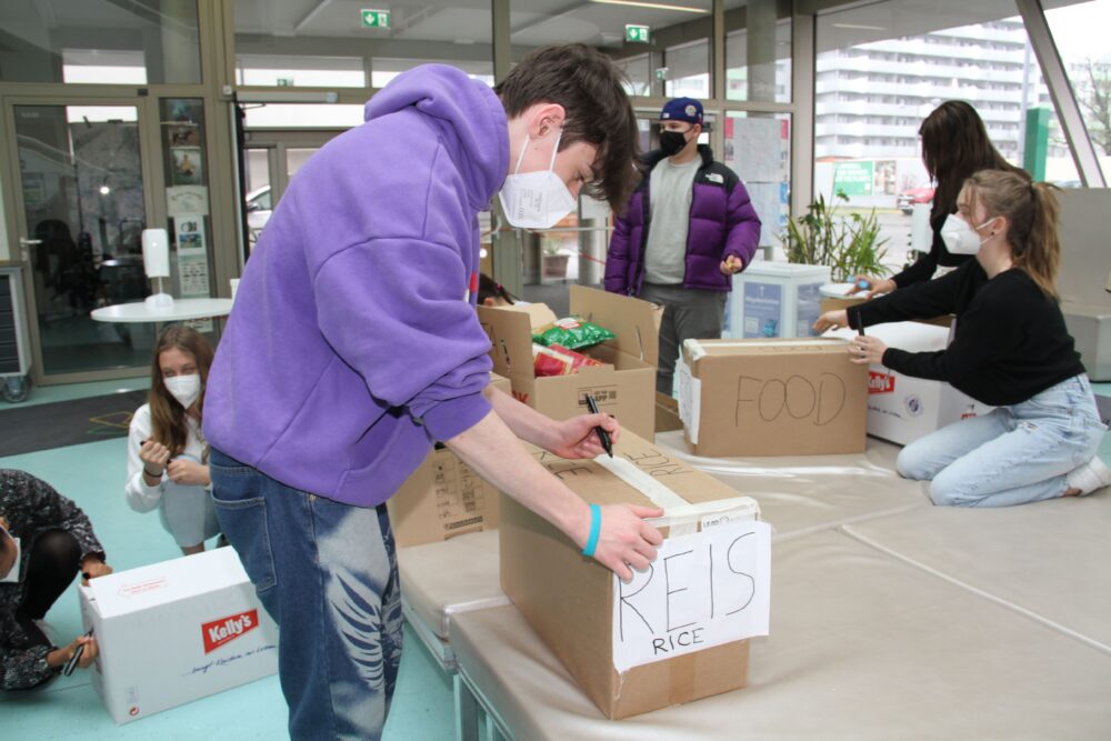 Jugendliche sortieren gespendete Gegenstände und beschriften die Pakete