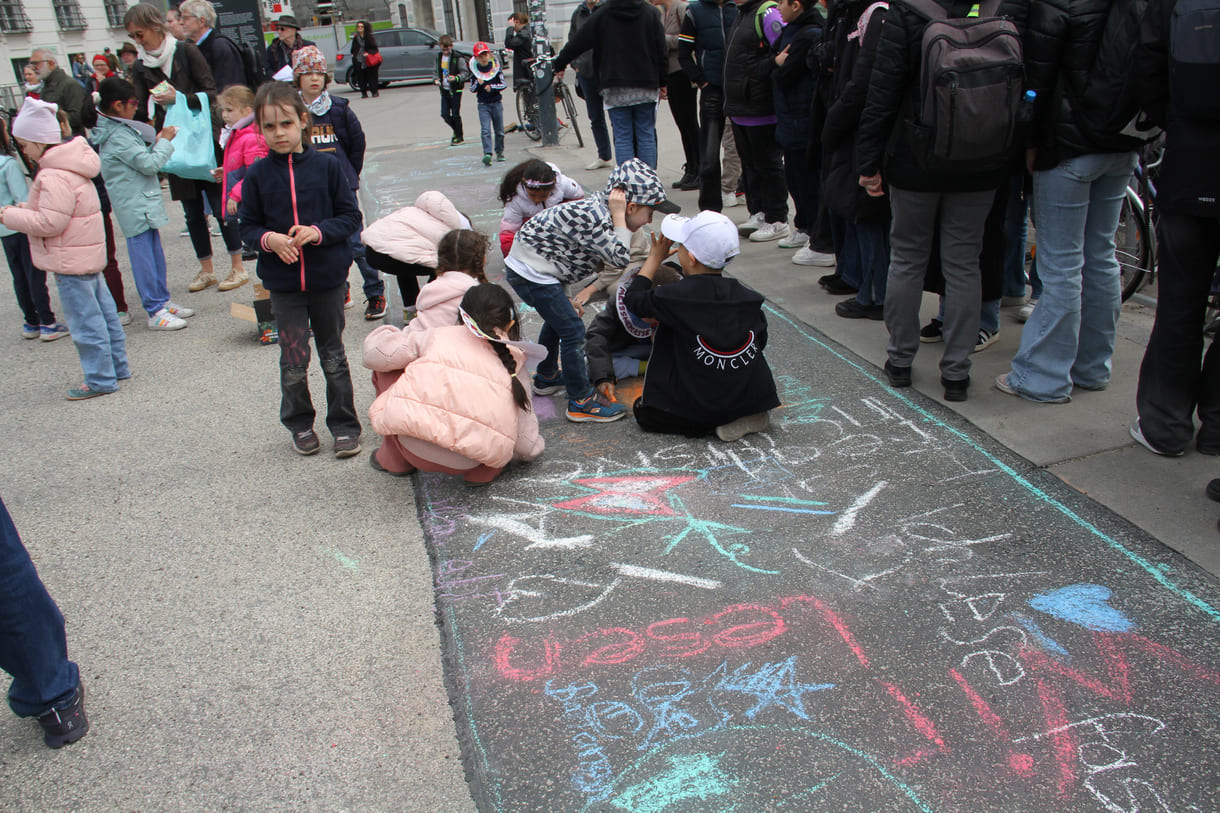 Kinder schreiben Kreidesprüche rund ums Lesen auf den Boden