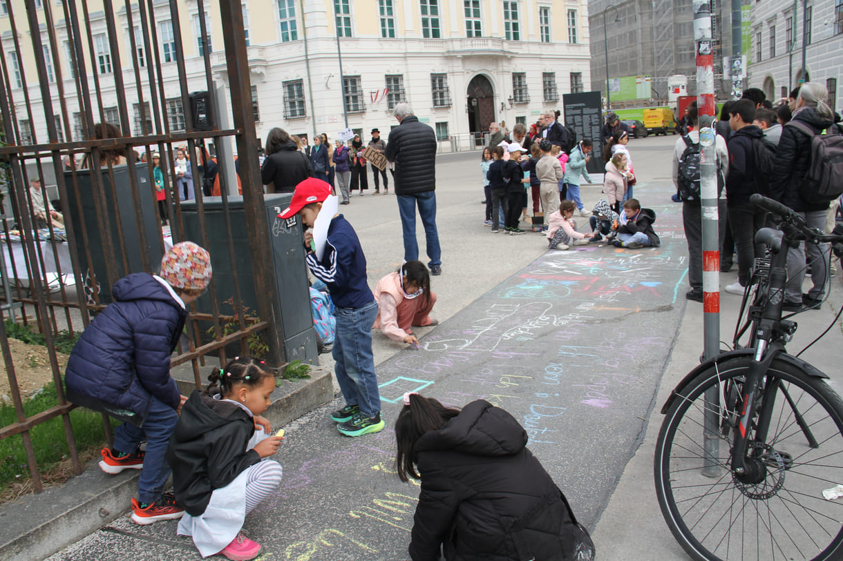 Kinder schreiben Kreidesprüche rund ums Lesen auf den Boden