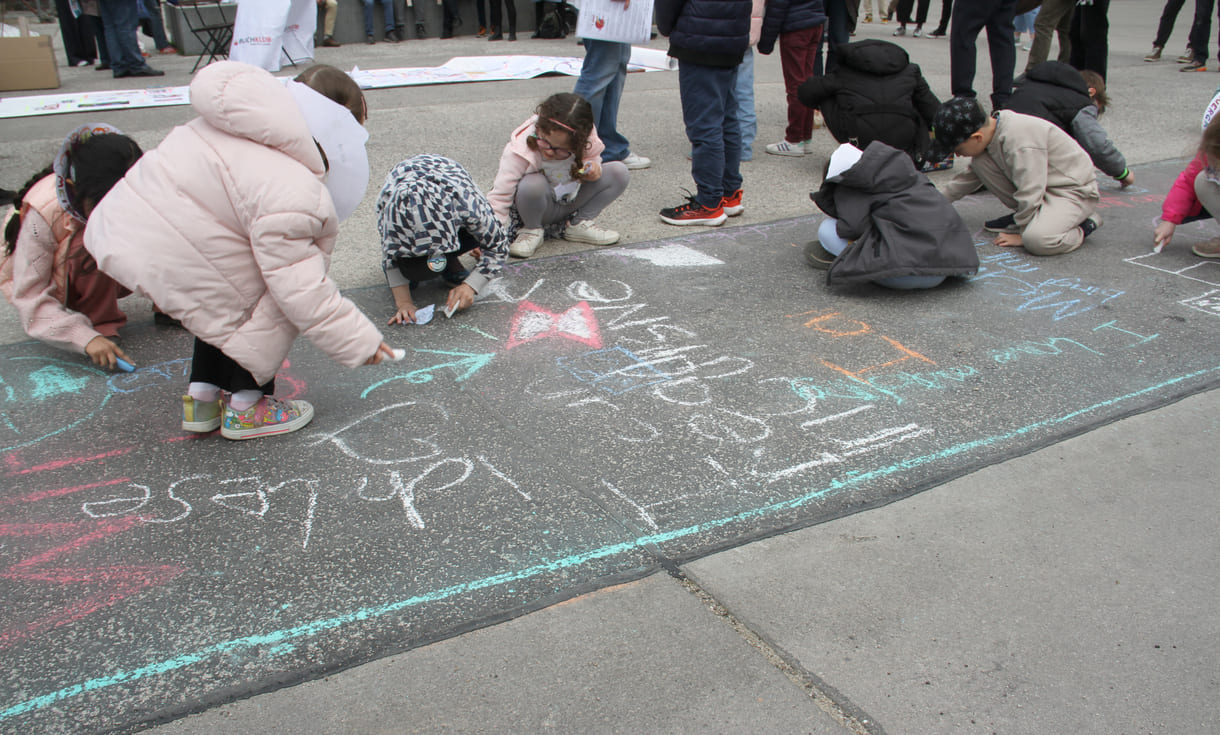 Kinder schreiben Kreidesprüche rund ums Lesen auf den Boden