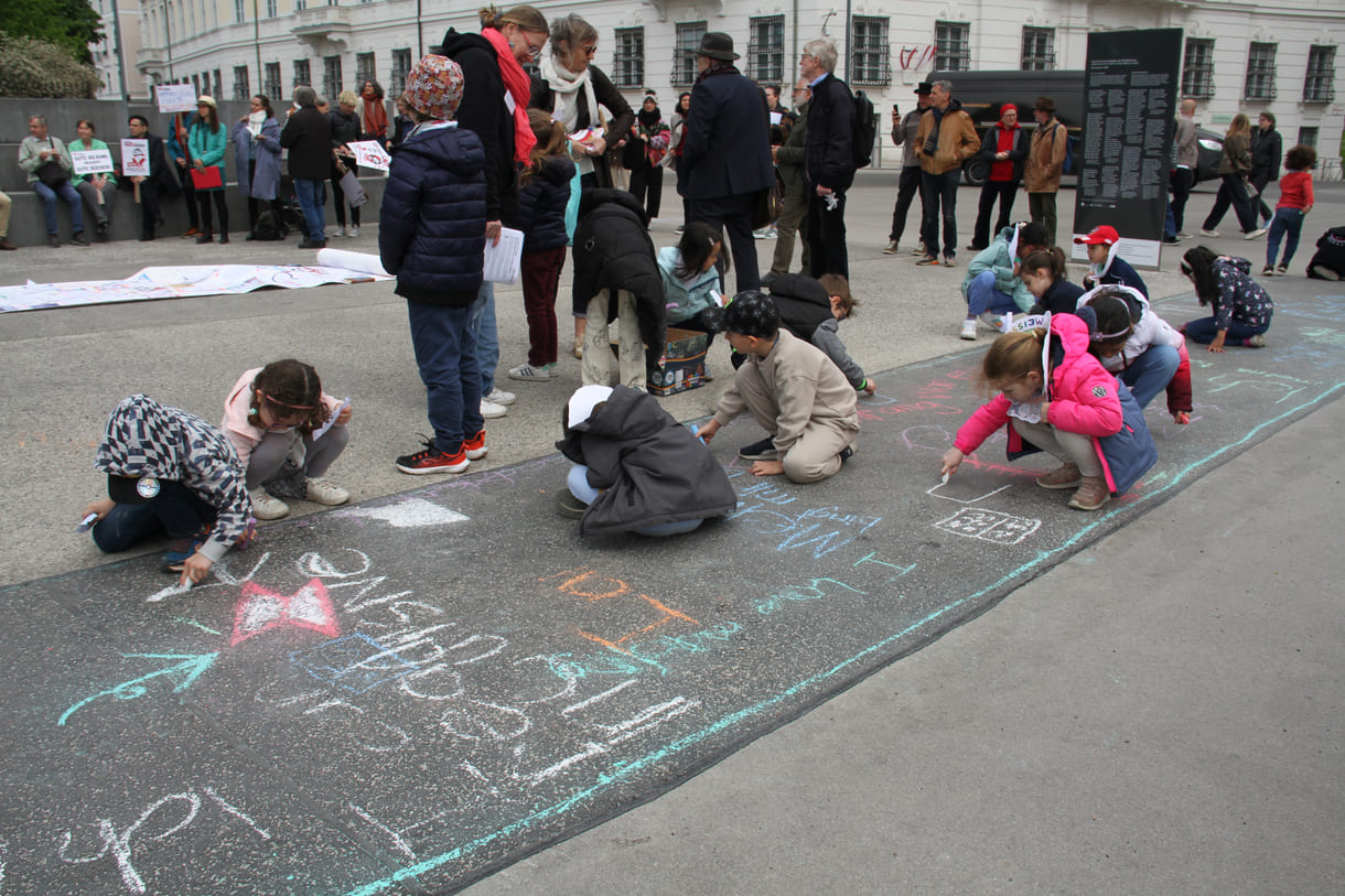 Kinder schreiben Kreidesprüche rund ums Lesen auf den Boden