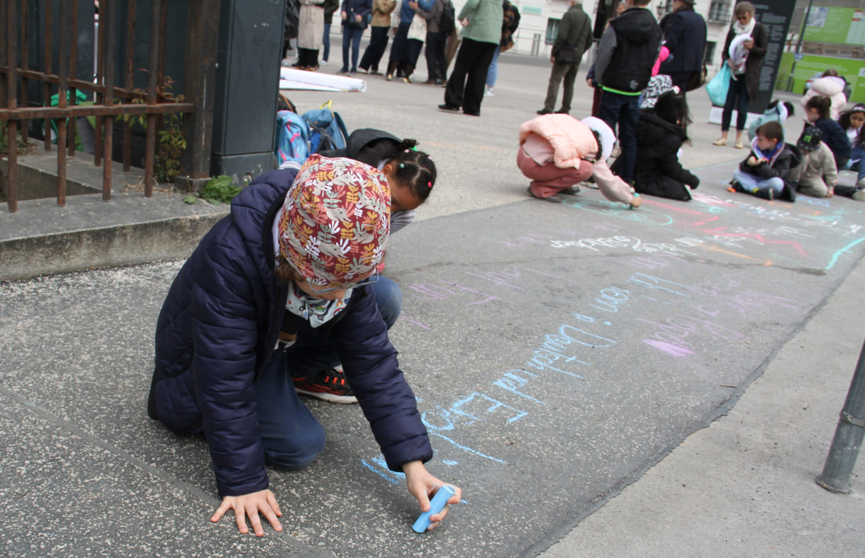 Kinder schreiben Kreidesprüche rund ums Lesen auf den Boden