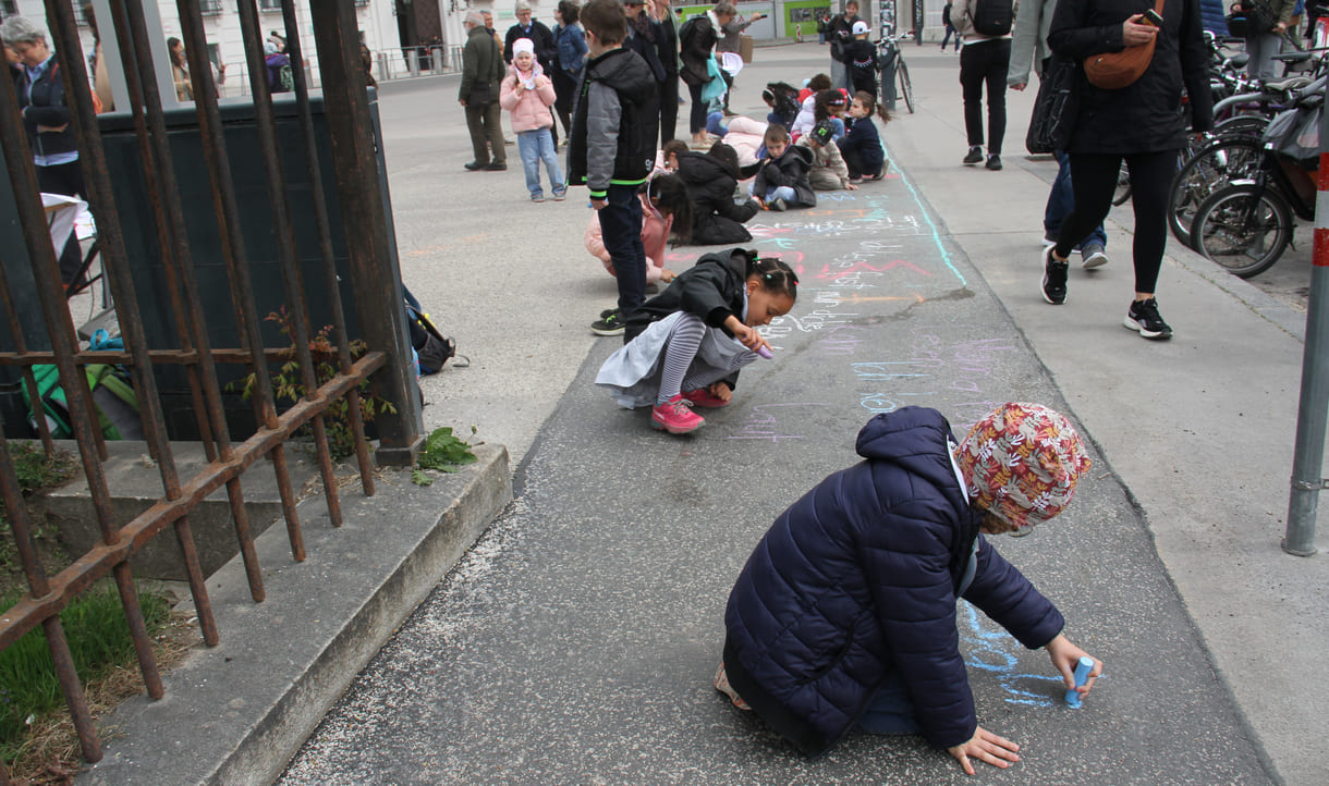 Kinder schreiben Kreidesprüche rund ums Lesen auf den Boden