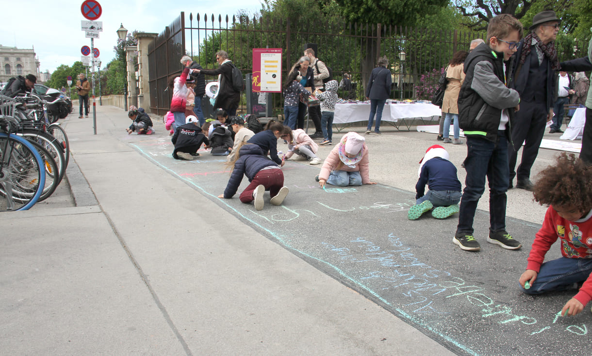 Kinder schreiben Kreidesprüche rund ums Lesen auf den Boden