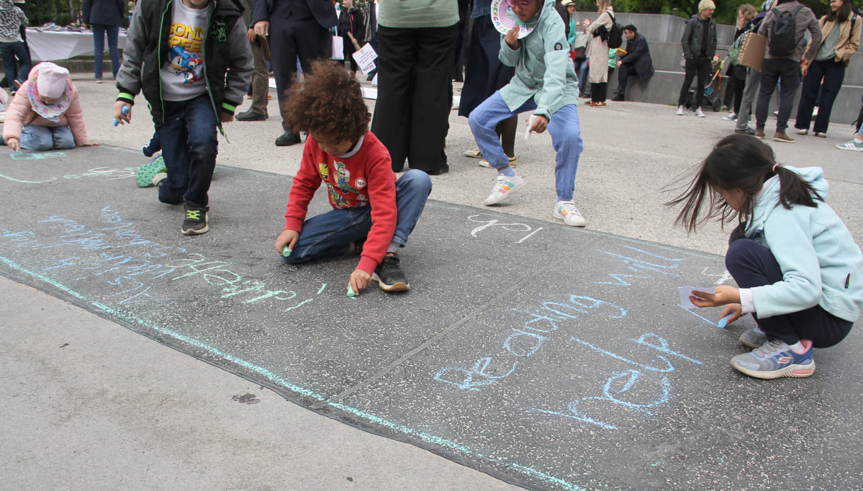 Kinder schreiben Kreidesprüche rund ums Lesen auf den Boden