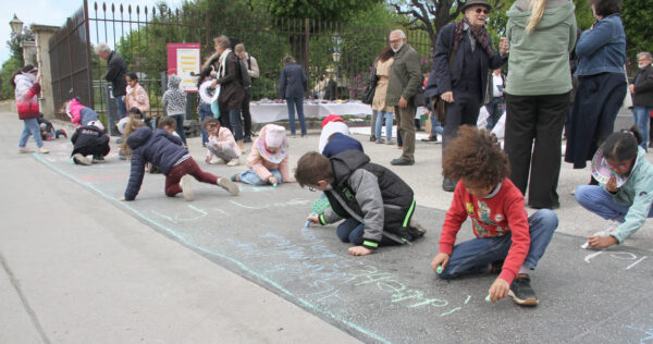 Kinder schreiben Kreidesprüche rund ums Lesen auf den Boden