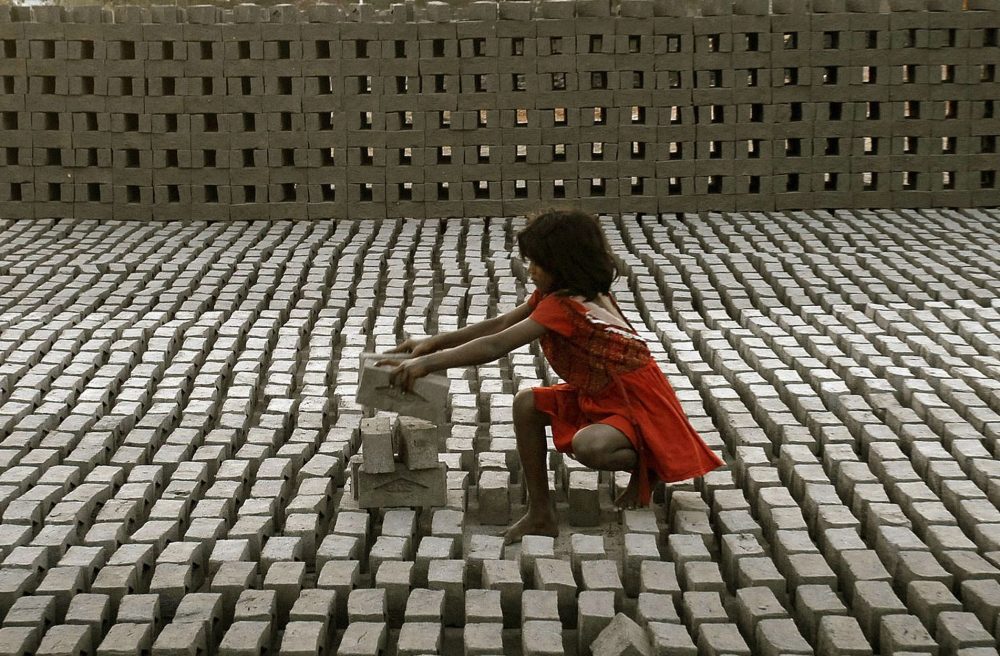 Ganz junges Mädchen schlcihtet Ziegel in einer Fabrik bei Hyderabad (Indien)